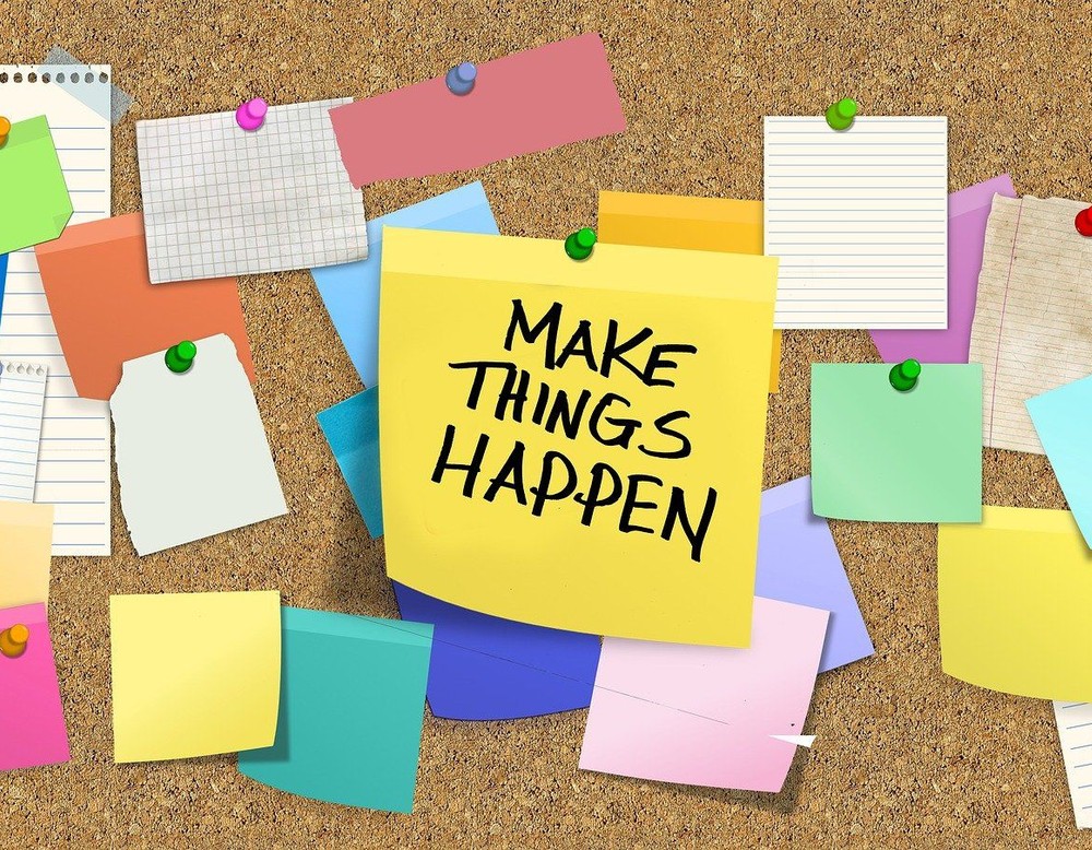 Die Übersicht einer Pinnwand mit bunten Zetteln. Der Mitte steht der Satz: "Make Things Happen":