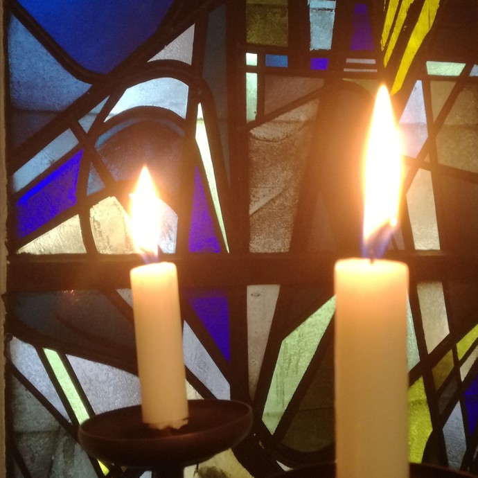 Brennende Kerzen vor einem Buntglasfenster
