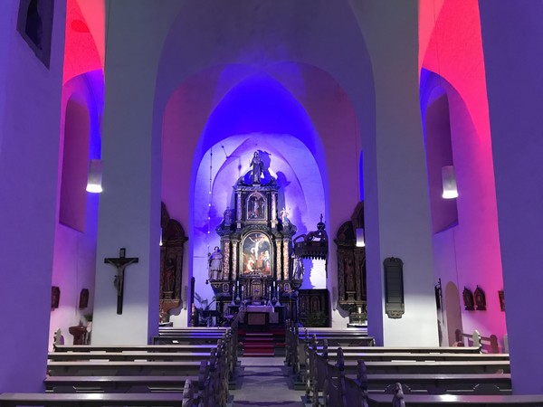 Der Hochaltar der Pfarrkirche St. Nikolaus. Das Innere der Kirche ist in blauem und rotem Licht erstrahlt.