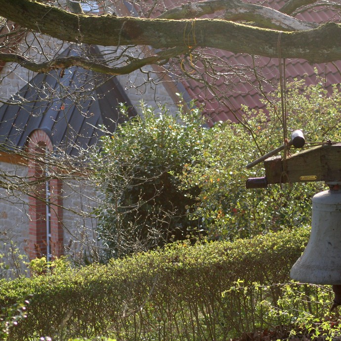 An einem Baum hängt die Glocke der Ökumenischen Lebensgemeinschaft in Bad Salzuflen. © Gunnar Stierle.