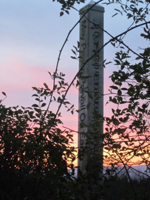 Säule bei Sonnenuntergang. Inschrift „May Peace Prevail On Earth“ („Möge Frieden sich auf Erden durchsetzen“). Foto: Agentur Herzstück.
