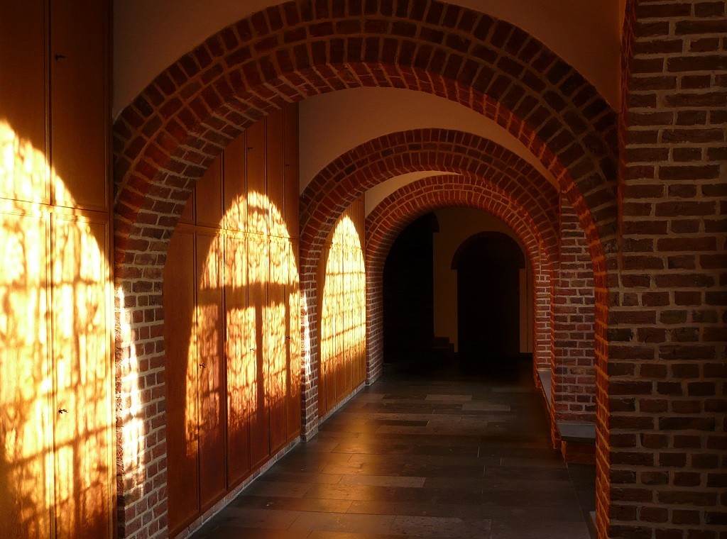 Eine Kerze im Pilgerkloster Werl. Im Hintergrund leuchten verschiedene Farben verschwommen.